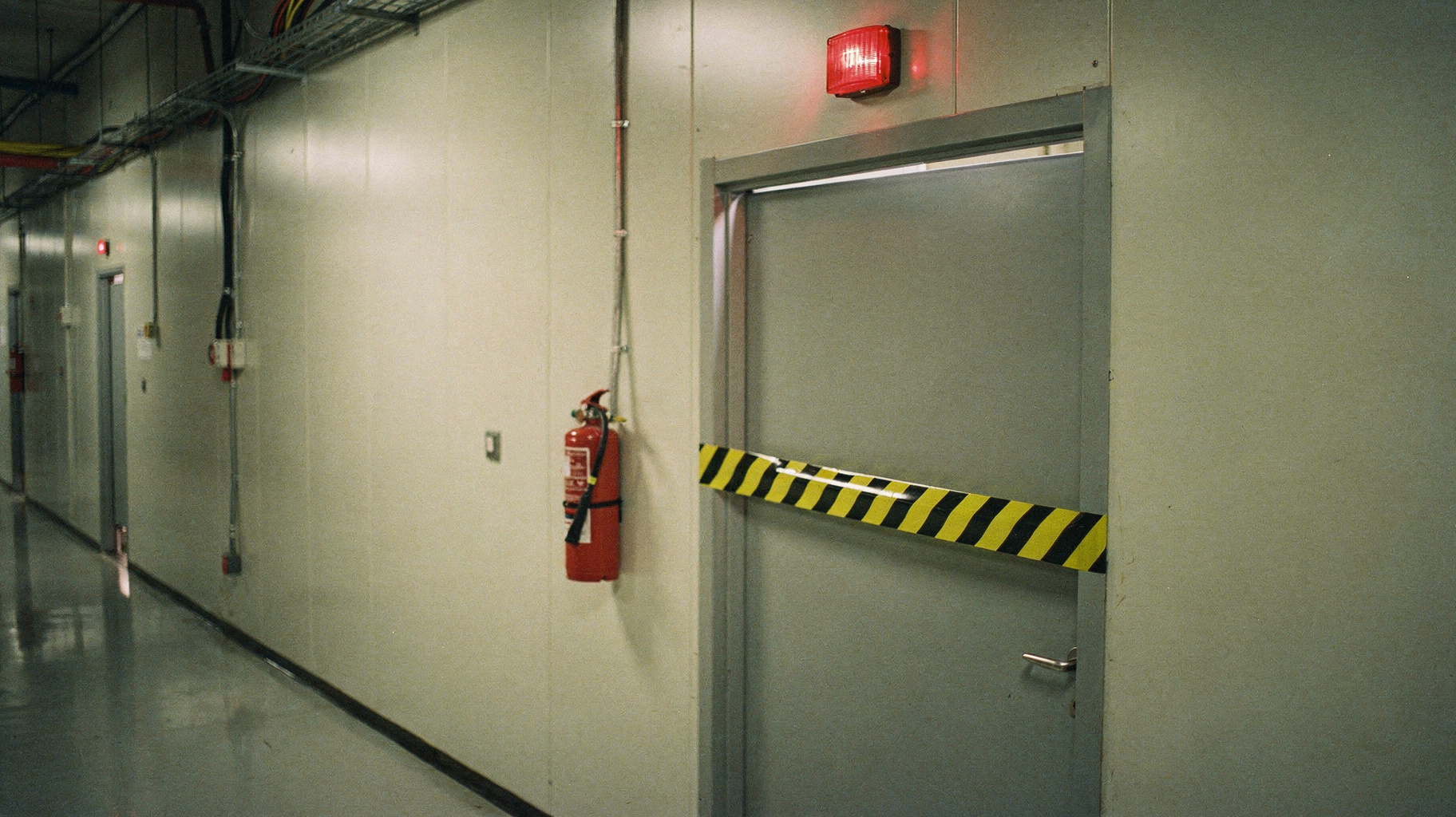 A sealed server-room door standing ajar with warning tape